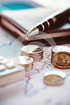 Closeup coins with line chart, pen and calculator