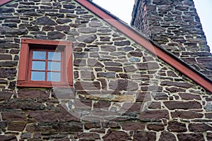 Closeup of colonial american stone  home antique window roofline and chimney