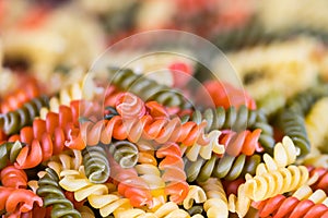 Closeup of colored spiral twisted fusilli pasta on pile with blurred background