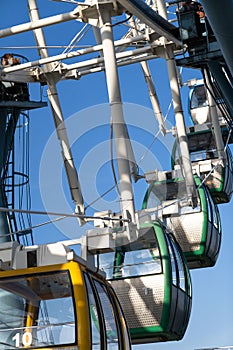 Closeup of colorful cabins of giant ferris wheel in amusement park against blue sky