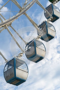 Closeup of colorful cabins of giant ferris wheel in amusement park against blue sky