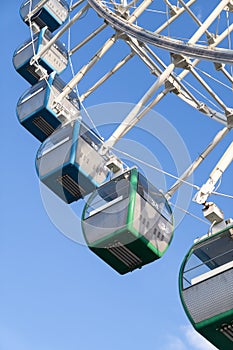 Closeup of colorful cabins of giant ferris wheel in amusement park against blue sky