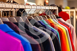 Closeup colorful male, female clothes in boutique hanging on hangers, clothing rack on metal stand. Concept opening