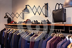 Closeup colorful male, female clothes, shoes in boutique hanging on hangers, clothing rack. Concept opening luxury shop
