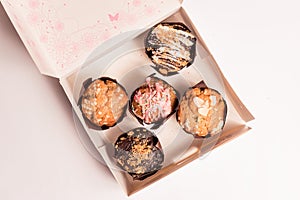 Closeup of colorful muffins and cupcakes box isolated on white background. muffins with chocolate and sugar glaze and icing,