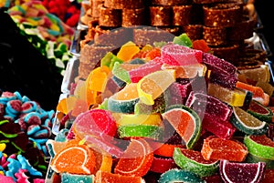 closeup of colorful sugar-coated jelly candy on display. street vendor stand. tasty fruit shapes slices