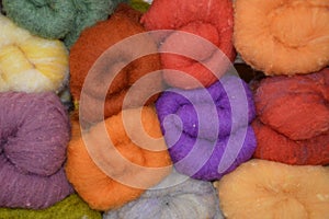 Closeup of colorful wools for felting on top of each other in a shelf