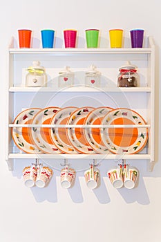 Closeup of Colourful Plates and Dinnerware in a Cupboard on Whit