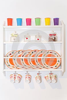 Closeup of Colourful Plates and Dinnerware in a Cupboard on Whit