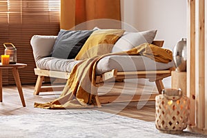 Closeup of comfortable Scandinavian sofa with futon and black and orange pillows