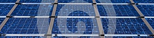 Closeup of commercial utility installation of blue photovoltaic panels on a sunny day, green power generation