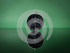 Closeup compass on green background with reflection