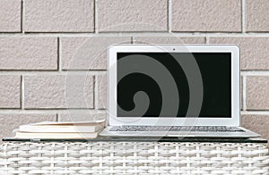 Closeup computer on blurred wood weave table and brown brick wall texture background , beautiful work place interior of house