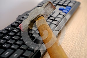 Closeup computer keyboard, iron hammer hits keys with force, breaks gadget, concept annoys slow Internet, freezing of computer