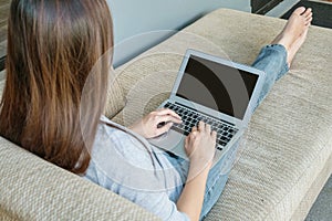 Closeup computer notebook on woman lap with sitting on sofa for work action in freelance work concept