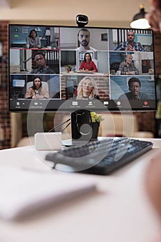 Closeup of computer screen with video conference app and webcam showing diverse team