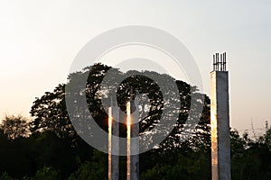 Closeup concrete columns reflect with the sunlight at the construction site with landscape and blue sky in background