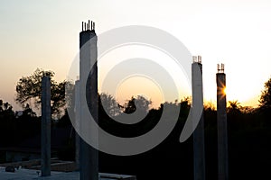 Closeup concrete columns reflect with the sunlight at the construction site with landscape and blue sky in background