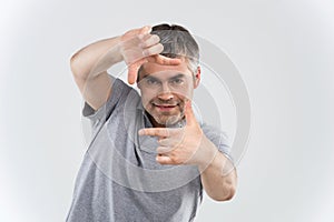 Closeup of confident happy man framing photograph white background.