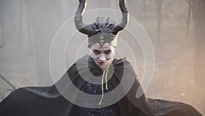 Closeup of a confused girl in the image of Maleficent in the misty forest