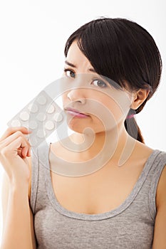 Closeup of confused young woman holding pills