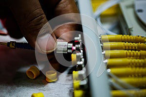 Closeup of connectors of optical fiber network cable. The laser shines from the optical cable