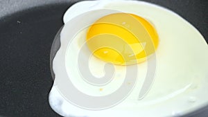 Closeup of cooking fried eggs in black frying pan. Breakfast concept.