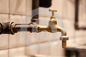 Closeup copper faucet, black industrial pipes on wall with white tiles. Concept designer bathroom in restaraunt, modern interior