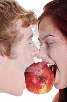 Closeup of couple biting apple.