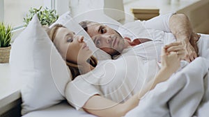 Closeup of couple with relationship problems having emotional conversation while lying in bed at home