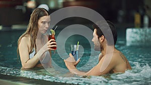 Young couple relaxing at whirlpool indoor. Attractive couple drinking cocktails