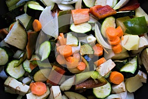 Closeup of courgettes, carrots, peppers, onion, aubergines and garlic cut ready to be cooked