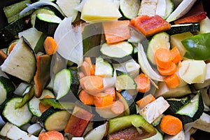 Closeup of courgettes, carrots, peppers, onion, aubergines and garlic cut ready to be cooked