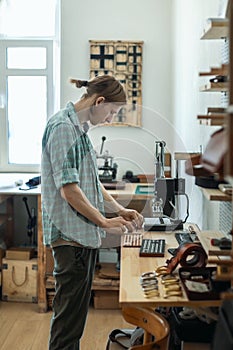 Closeup craftsman hands typing text for branding leather with personal stamp. Creating craft label