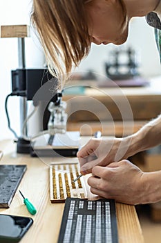 Closeup craftsman hands typing text for branding leather with personal stamp. Creating craft label