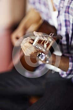 A closeup on creativity. A handsome young musician playing a guitar.