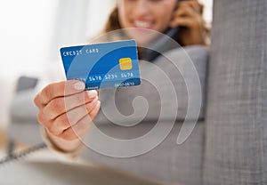 Closeup on credit card in hand of young woman talking phone