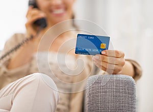 Closeup on credit card in hand of young woman talking phone