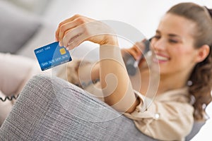 Closeup on credit card in hand of young woman talking phone