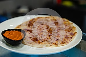 A closeup of Crispy Onion Dosa with Tangy Tomato Chutney