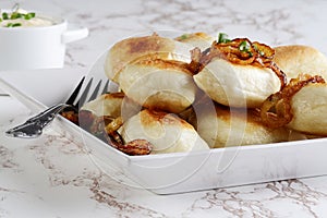 Closeup crispy pierogies with spring onions on a plate