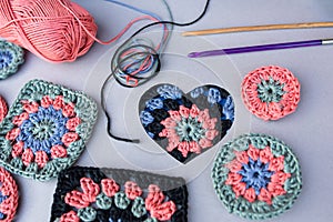 Closeup of crochet pattern in a heart, two hooks and other patterns