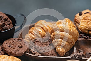 Closeup of Croissant with chocolate chip cookie on wooden plate