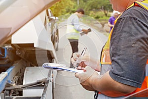 Closeup and crop insurance agent writing on clipboard while examining car after accident claim being assessed and processed on