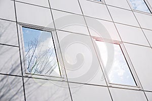 Closeup and crop reflection and shadow of winter tree and bright blue sky on office building windows