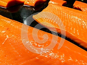 Closeup and crop of salmon meat slice for sale on black tray