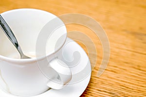 Closeup and crop white coffee cup and spoon with saucer on wooden table