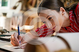 Closeup and crop young female leather goods maker is drawing a design on leather in leather workshop