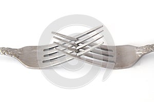 Closeup of the crossed tines of two forks. White background selective focus