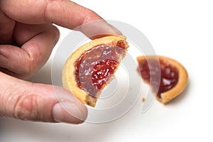 crunched mini tartlets with strawberry jam in hand on white background